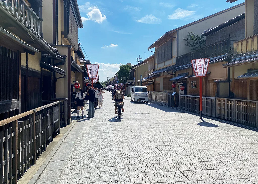 昼間の祇園花見小路。石畳の道を地元の人が自転車で走っている。