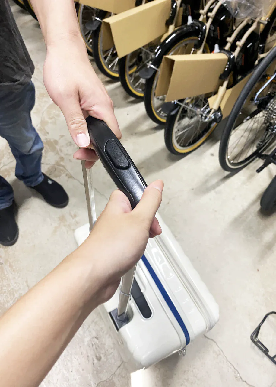 「荷物」預かりオプションを利用するために、店舗スタッフに持参したキャリーケースを預けている様子。