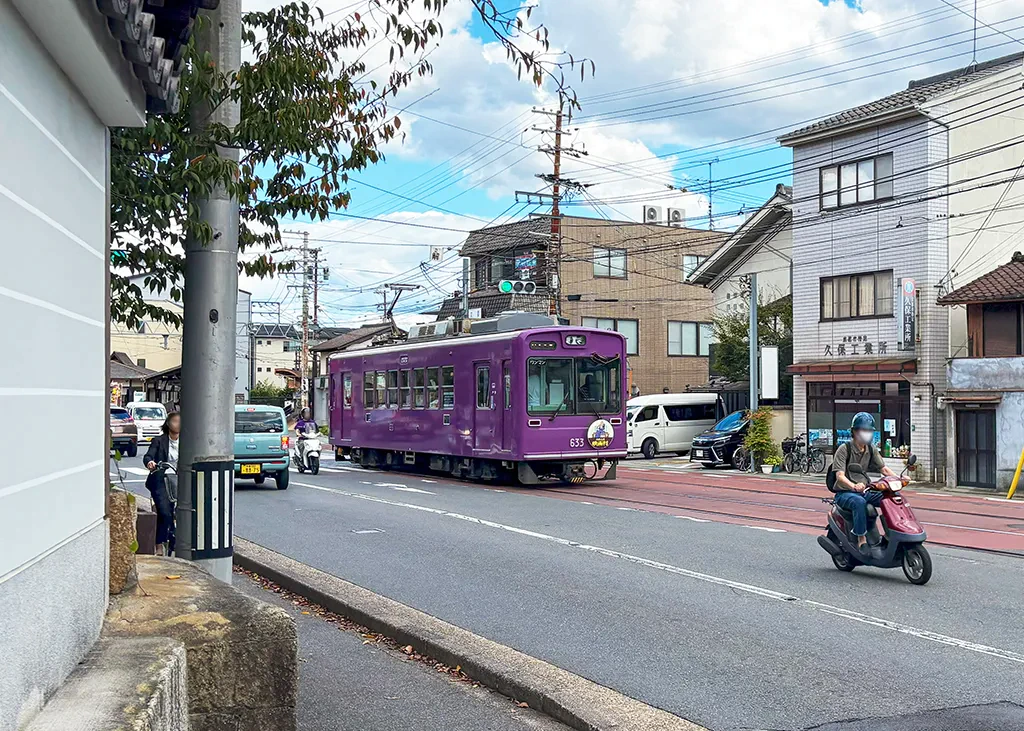 嵐電の路面区間。紫色の電車が道路を走っている。